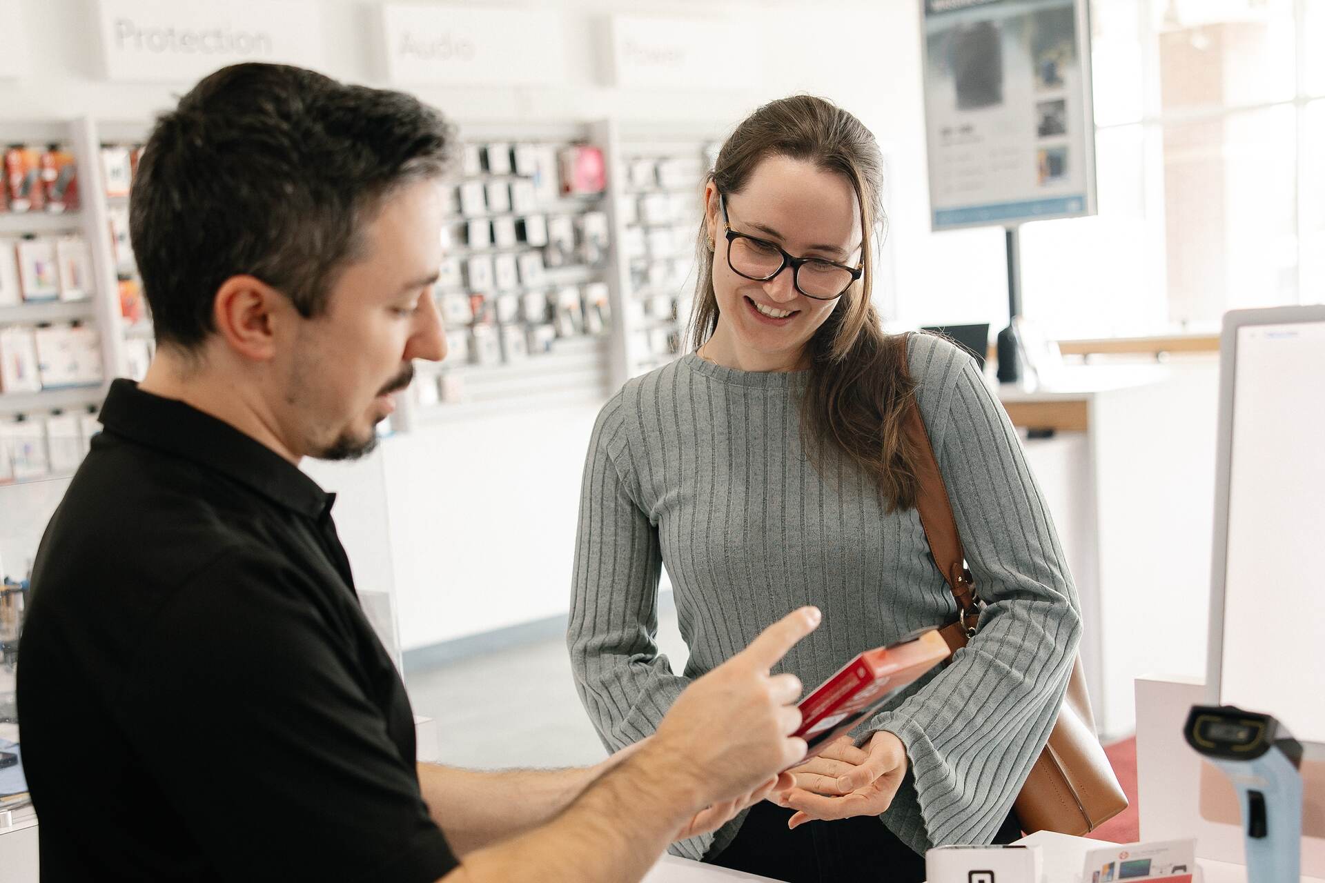 A customer handing a device across the counter to a MyRepairStore technician
